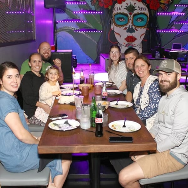 A group of people, including a child, sitting around a table with drinks and plates in a restaurant.