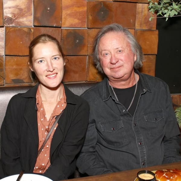 A man and woman seated at a restaurant table, smiling at the camera.