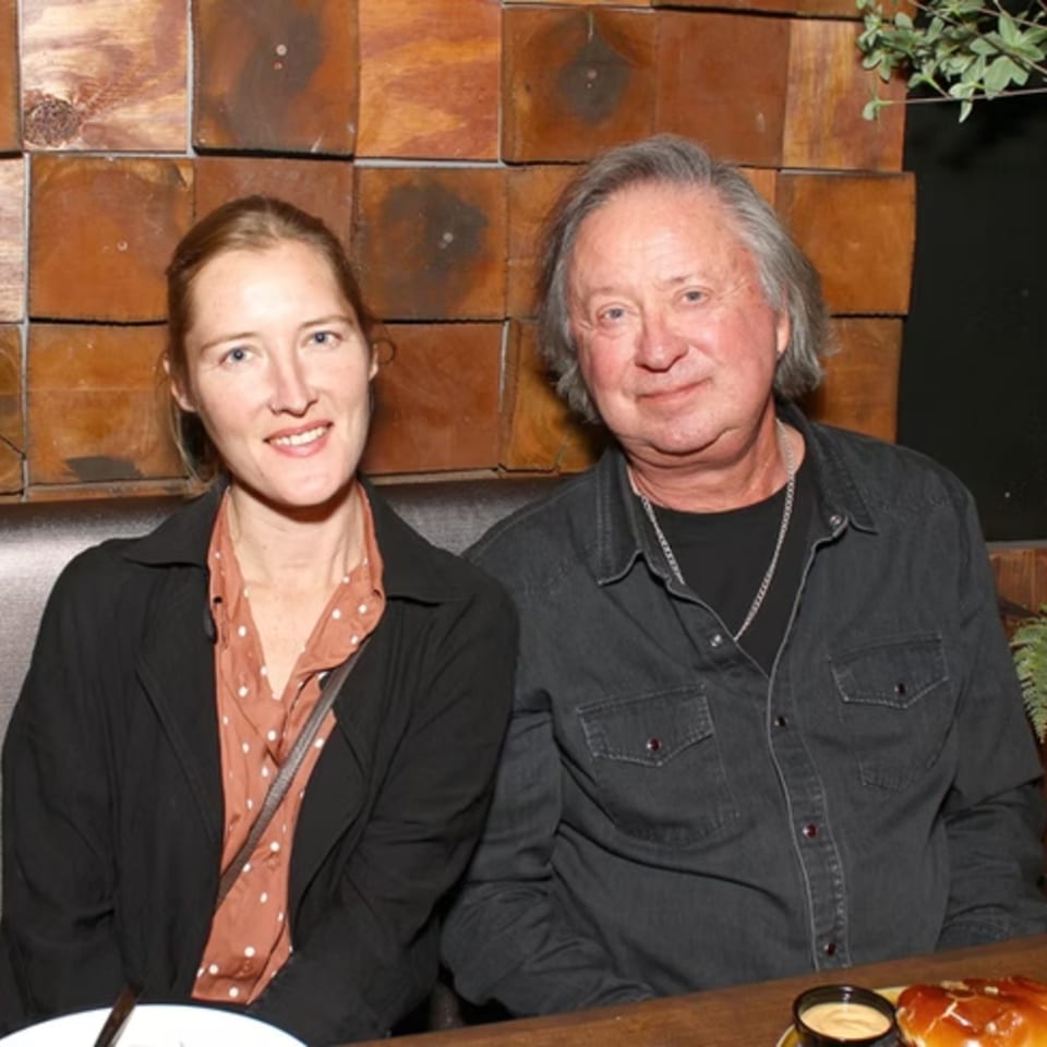 A man and woman seated at a restaurant table, smiling at the camera.