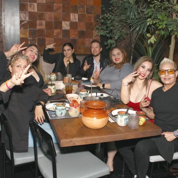 Group of friends enjoying a meal at a restaurant, with traditional Mexican pottery on the table.