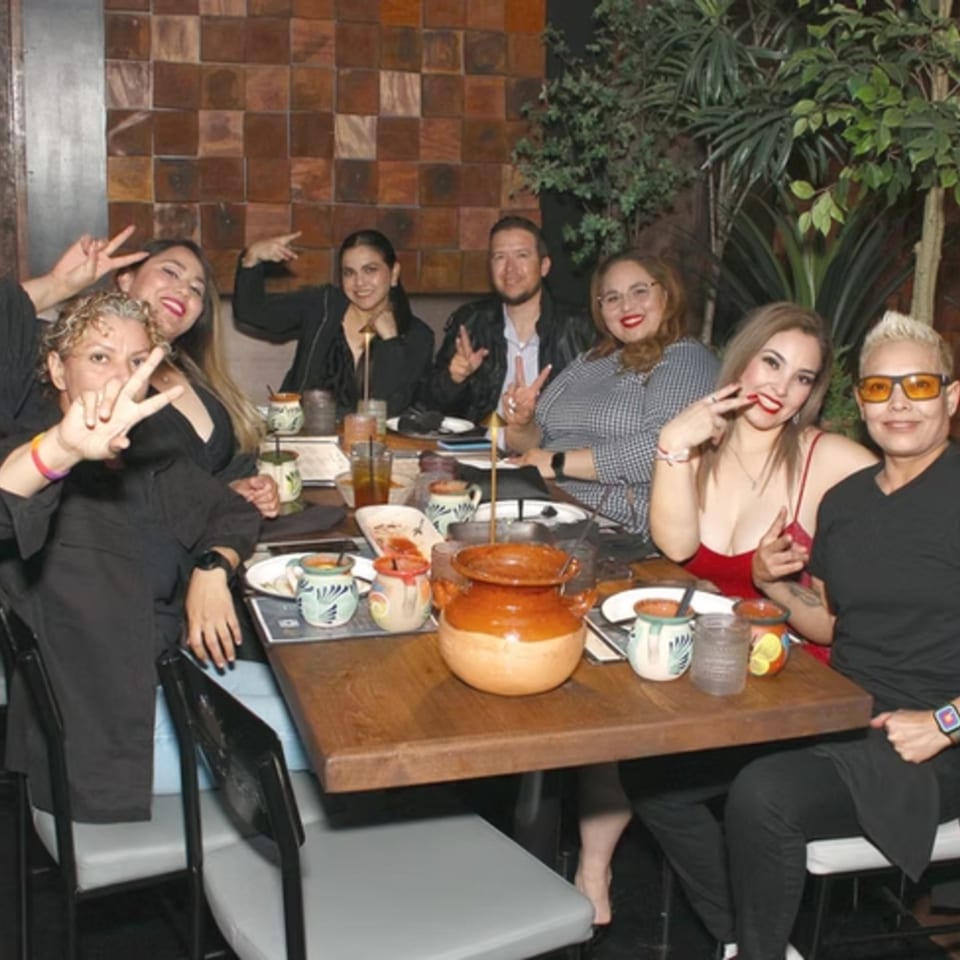 Group of friends enjoying a meal at a restaurant, with traditional Mexican pottery on the table.